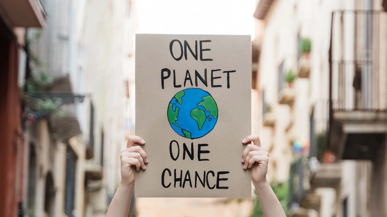 Eine Person hält ein Schild mit der Aufschrift "One Planet One Chance"
